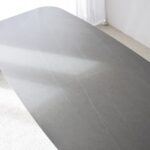 Mesa de comedor oval de sobre cerámico gris con patas fresno