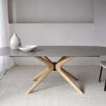Mesa de comedor oval de sobre cerámico gris con patas fresno